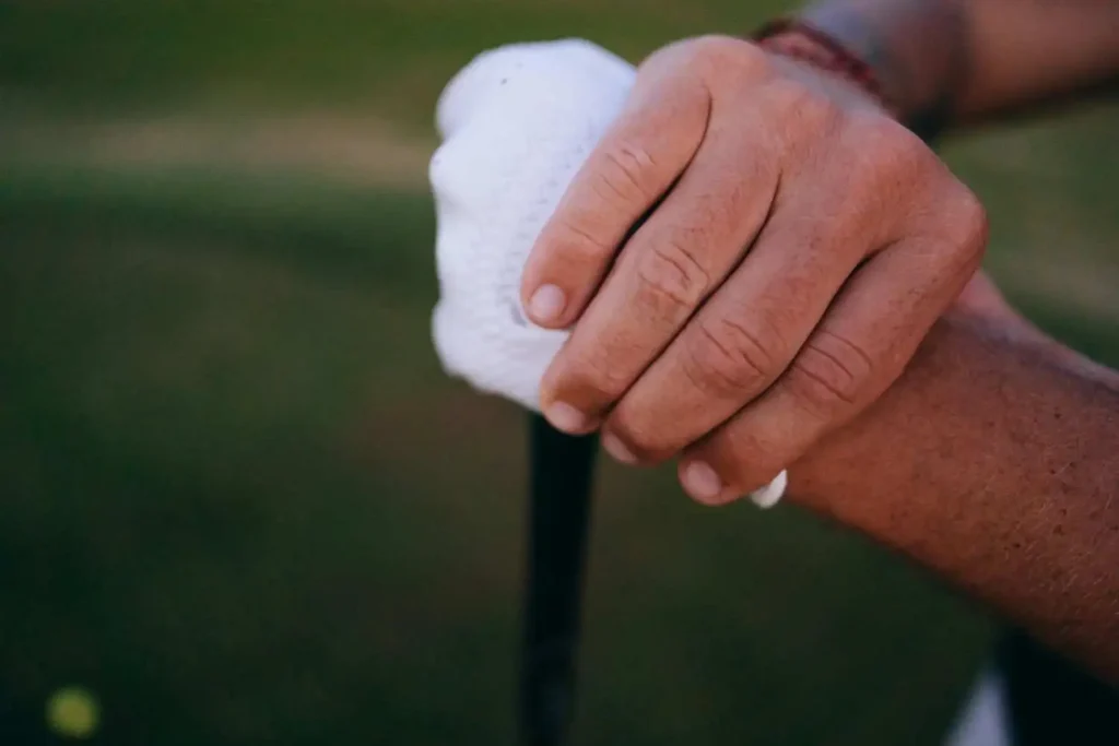 Close-up of a golfer’s hands gripping a club with a soft glove, just to show whot to maintain properly a putter grip