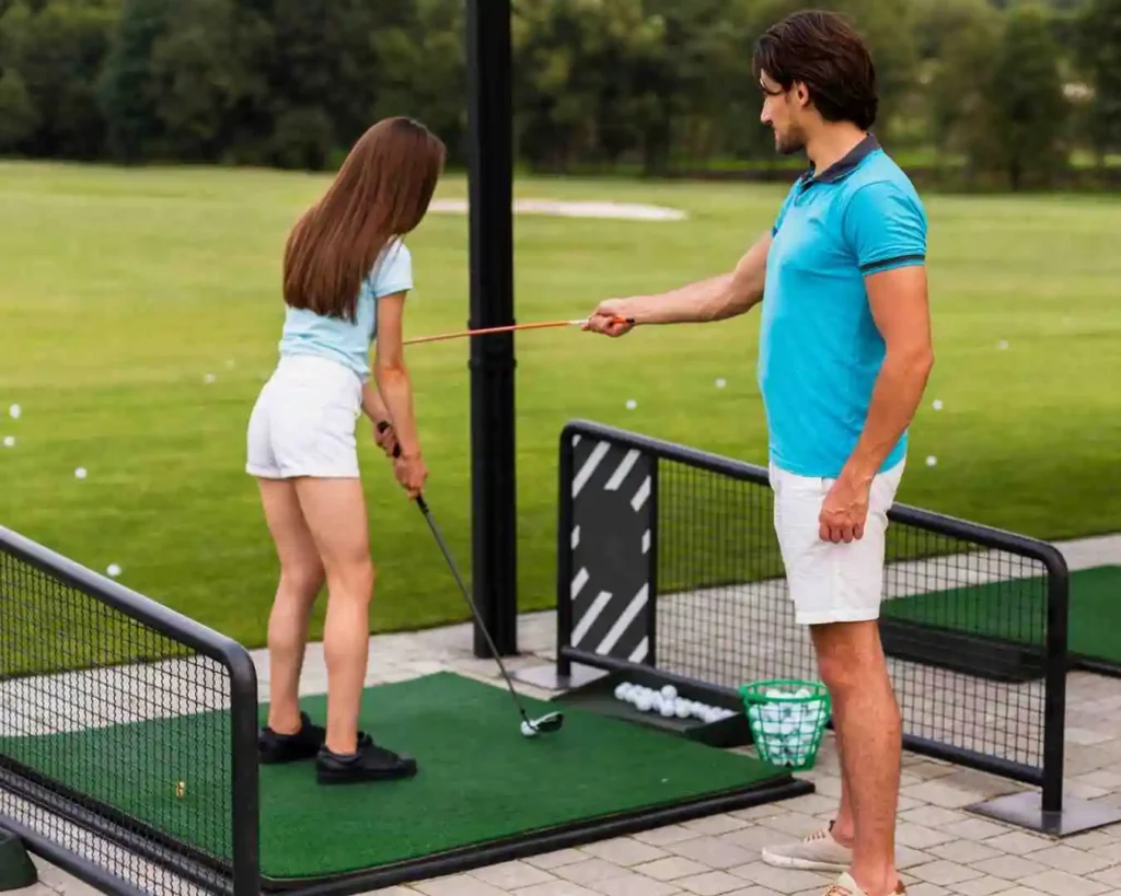 A golf trainer teaching a beginner golfer how to perfect their swing for Spornia Golf Net practice