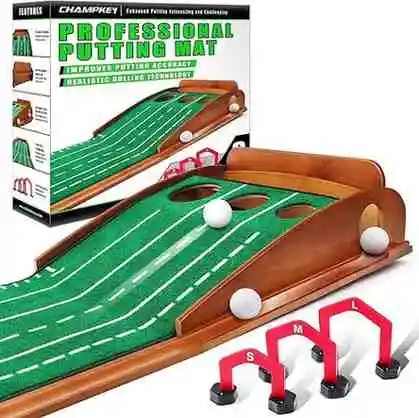 A Champkey Professional Putting Mat is shown. The mat is green with white alignment lines and features three holes at the end, each with a slightly different incline. Three white golf balls are positioned on the mat. In the foreground, there are three red putting gates labeled "S," "M," and "L." The product's packaging box is visible in the background.