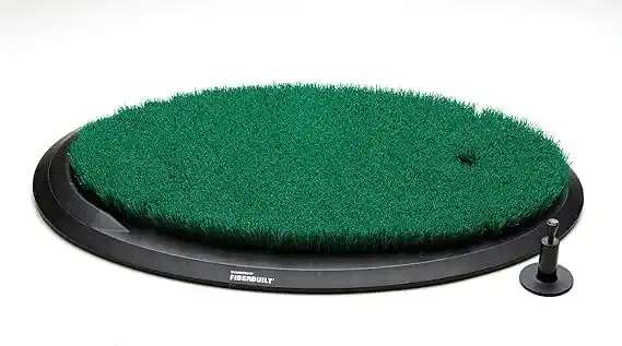 Fiberbuilt golf mat: An oval-shaped green golf hitting mat with a black base and a black tee holder to the right, against a white background.