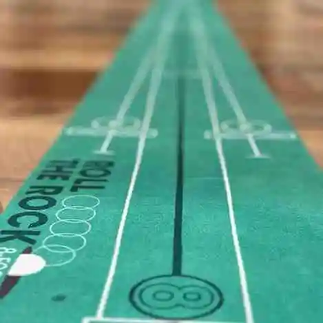 Close-up of a green EyeLine Golf putting mat with white alignment lines and "ROLL THE ROCK" text.